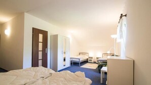 Una habitación de hotel con cama, escritorio, silla, armario y espejo.