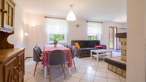 Un comedor con una mesa dispuesta para cuatro, un sofá, una mesita y un armario.