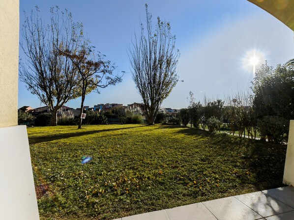 A grassy outdoor area with trees and a clear sky. - Lakeside Haven in Le Barcares (Le Barcares)