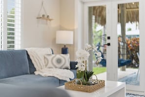 Ein Wohnzimmer mit einem blauen Sofa, einem weißen Couchtisch mit einem gewebten Korb und einer Topf-Orchidee.