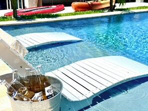 Ein Poolbereich mit einer Holzliege, einem Eimer voller Bierflaschen und einem roten Kajak im Hintergrund.