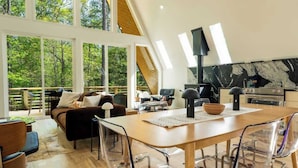 Ein modernes Interieur mit Essbereich, Küche und großen Fenstern mit Blick auf einen Wald.