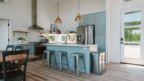 A modern kitchen with a central island, stainless steel appliances, and a view to the outside. - The Perch | Poolside Modern Mountain Retreat (Young Harris)