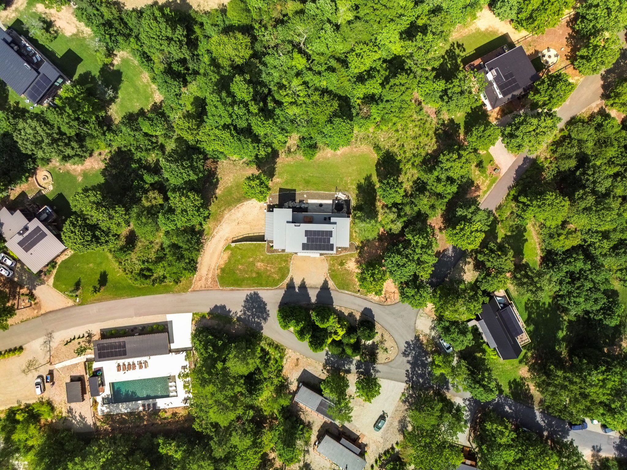 An aerial view of a residential area with multiple houses, roads, and green spaces.