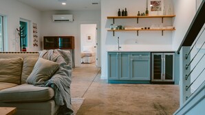 A modern living room with a sofa, a kitchen with blue cabinets, and a staircase. - The Perch | Poolside Modern Mountain Retreat (Young Harris)