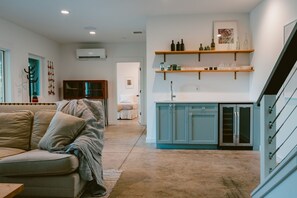 Ein modernes Wohnzimmer mit einer Couch, eine Küche mit blauen Schränken und eine Treppe.