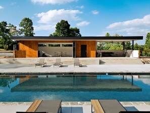 Ein moderner Poolbereich im Freien mit Liegestühlen und einer überdachten Sitzgelegenheit.