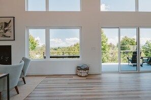 Ein geräumiges Zimmer mit großen Fenstern, einem Kamin und Blick auf Grünflächen.