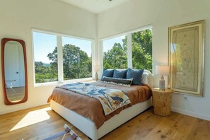 Ein Schlafzimmer mit einem großen Bett, zwei Fenstern, einem Spiegel und einer gerahmten Karte an der Wand.