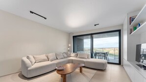Un salón moderno con un sofá modular, una mesa de centro y un amplio ventanal corredero que da a un espacio exterior.