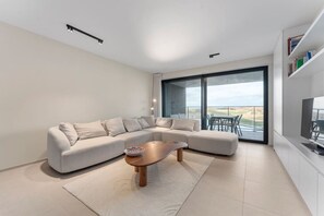 Un salón moderno con un sofá modular, una mesa de centro y un amplio ventanal corredero que da a un espacio exterior.
