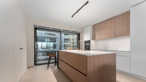 Una cocina moderna con una isla grande, armarios de madera y vistas a través de un ventanal.
