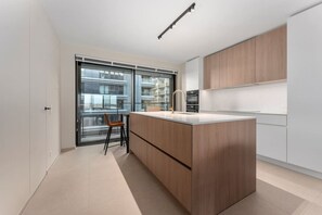 Una cocina moderna con una isla grande, armarios de madera y vistas a través de un ventanal.