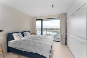 Un dormitorio moderno con una cama grande, un armario y un balcón con vistas.
