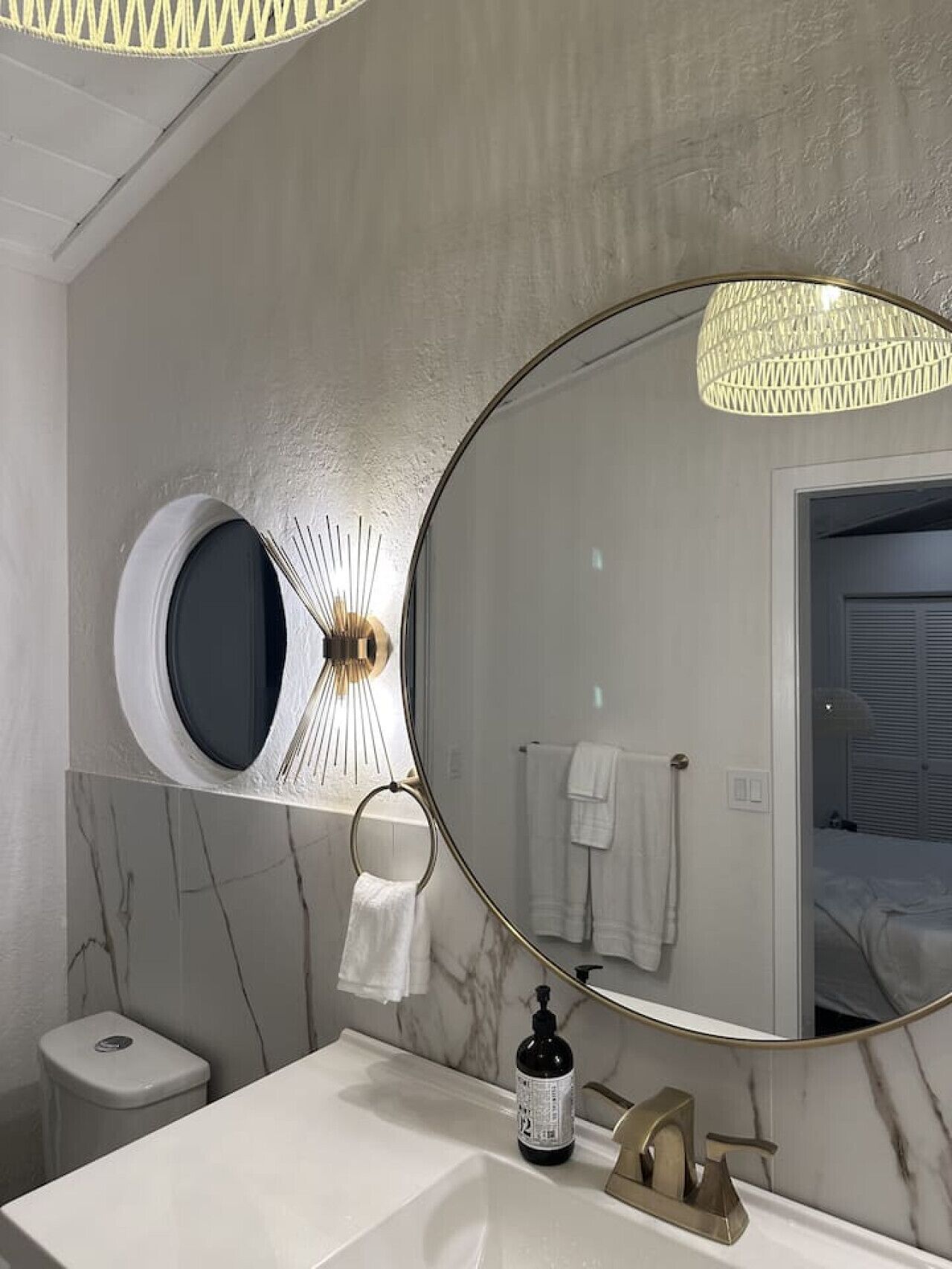 Une salle de bain avec un grand miroir, un lavabo rond, des toilettes et un porte-serviettes.
