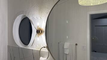 Une salle de bain avec un grand miroir, un lavabo rond, des toilettes et un porte-serviettes.