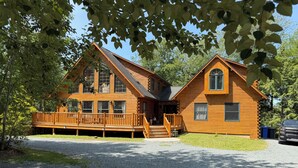 A two-story log cabin with a deck and a covered porch. - The Cozy Cabin Nook - Heart of Fall River (Fall River)