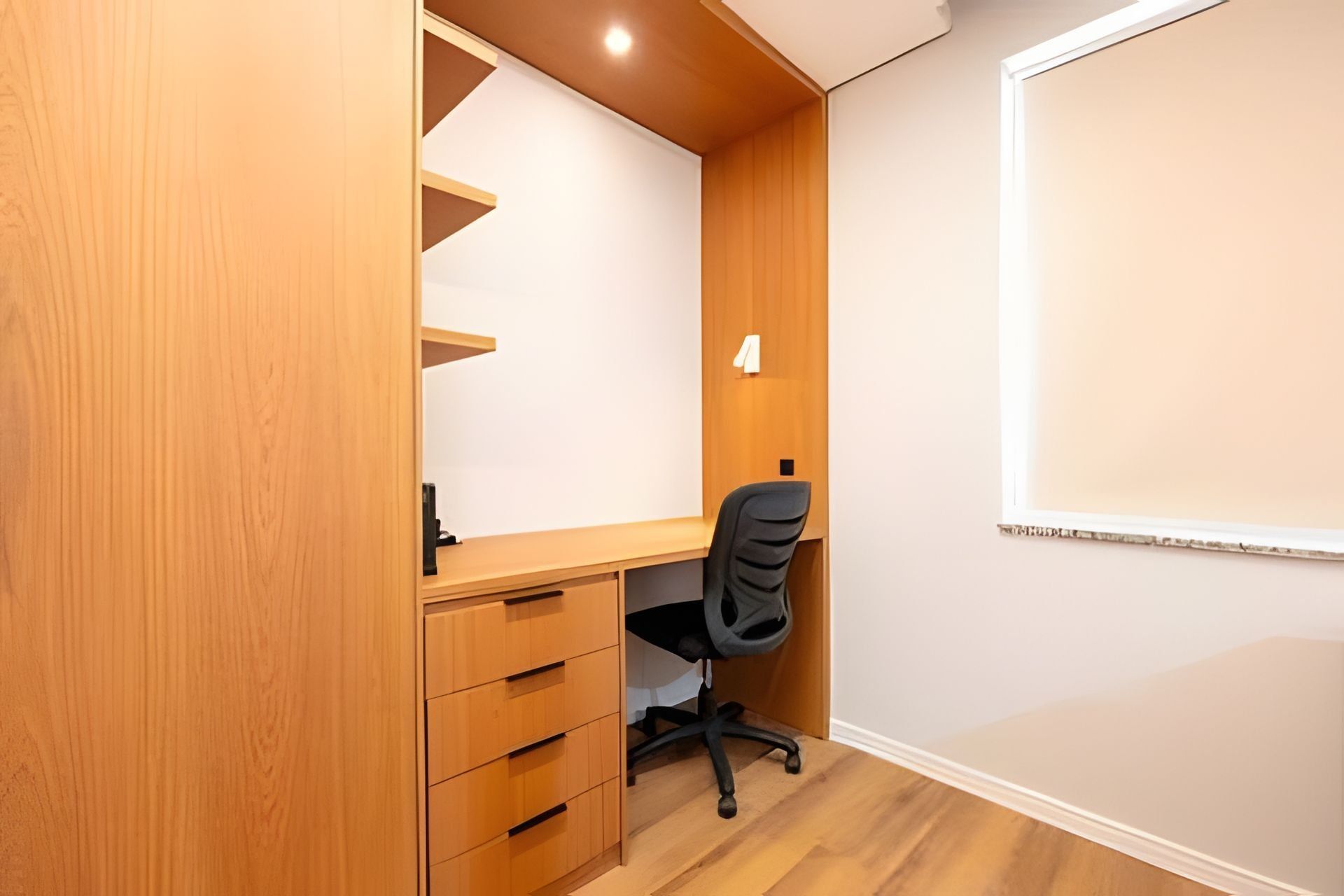 A compact office space with a desk, chair, and built-in shelving.