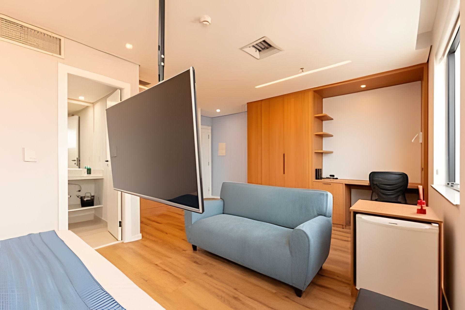 Una habitación moderna con sofá, escritorio y un refrigerador pequeño.