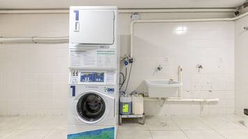 A public laundry facility with a washing machine, a sink, and a toilet.