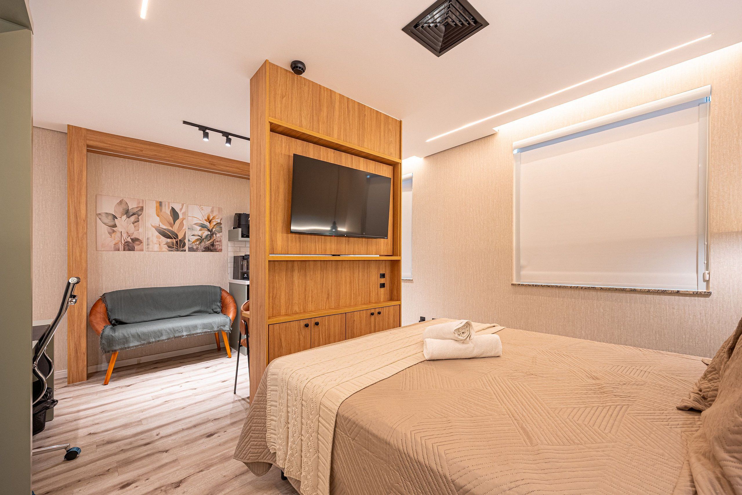 Une chambre à coucher comprenant un lit, une télévision, un canapé et une armoire en bois.