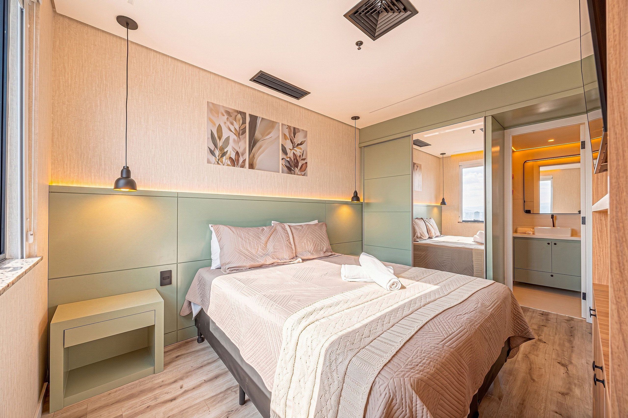 A modern bedroom with a large bed, bedside tables, a mirror, and a walk-in closet.