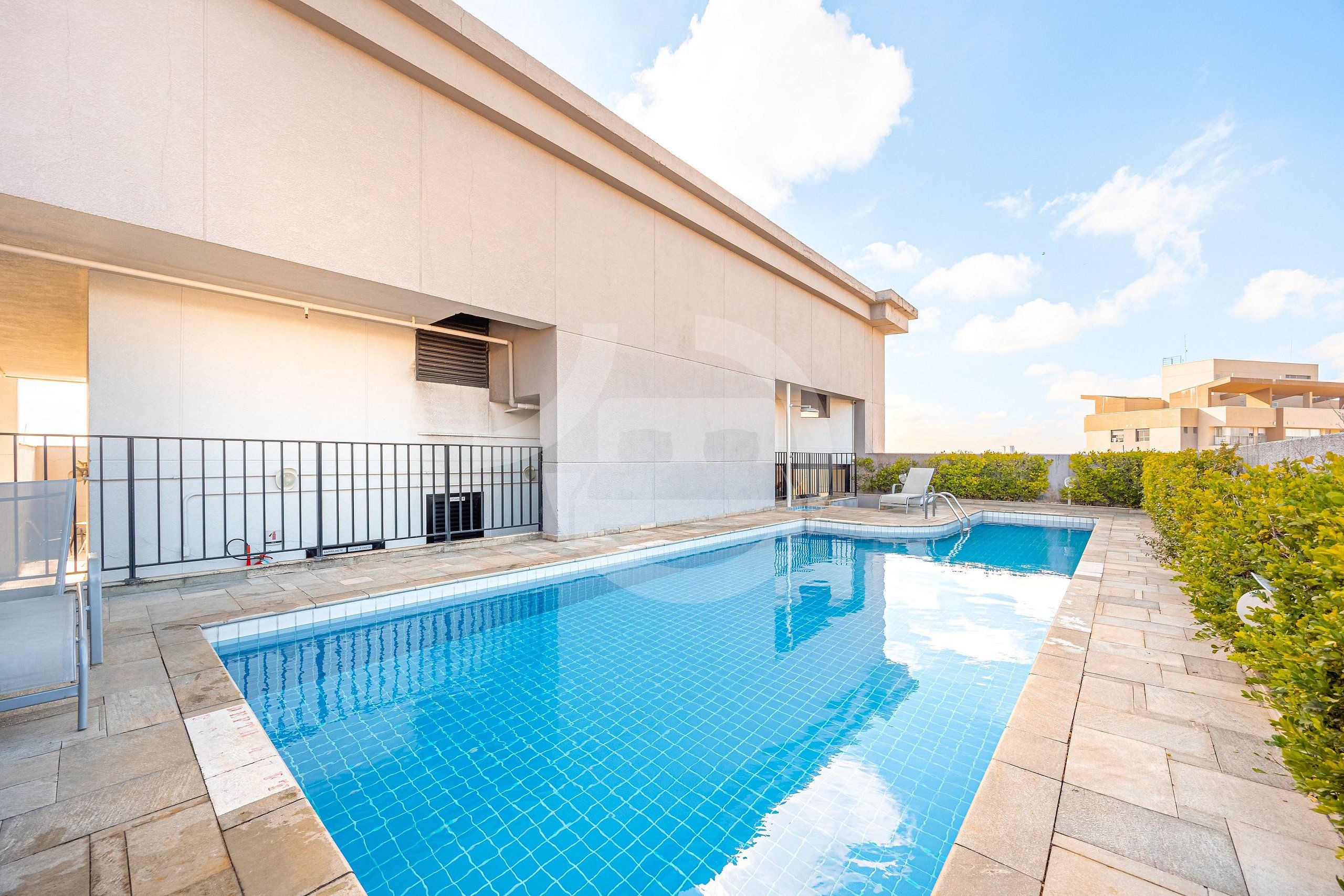 A modern building with a swimming pool, a covered area, and a clear sky.