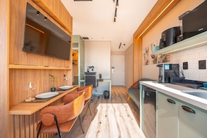 Cozinha moderna com área de jantar, eletrodomésticos embutidos e TV de tela plana.