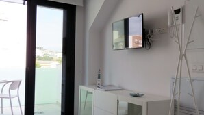 Ein modernes Badezimmer mit Glasdusche, einem weißen Waschtisch mit Spiegel und Blick auf den Außenbalkon.