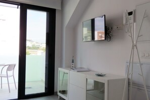 Ein modernes Badezimmer mit Glasdusche, einem weißen Waschtisch mit Spiegel und Blick auf den Außenbalkon.