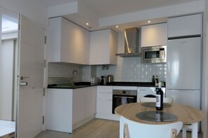 Eine moderne Küche mit weißen Schränken, einer Edelstahl-Mikrowelle und einem eingebauten Backofen.