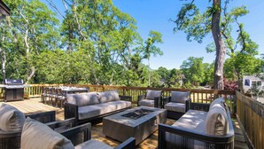 Une terrasse extérieure aménagée avec du mobilier, un barbecue et une vue sur les arbres et une maison.