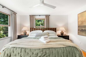 A neatly made bed with a green bedspread, two bedside lamps, a ceiling fan, and a window with curtains. - 1 Mile to Campground Beach, Dog Friendly, AC! (Eastham)