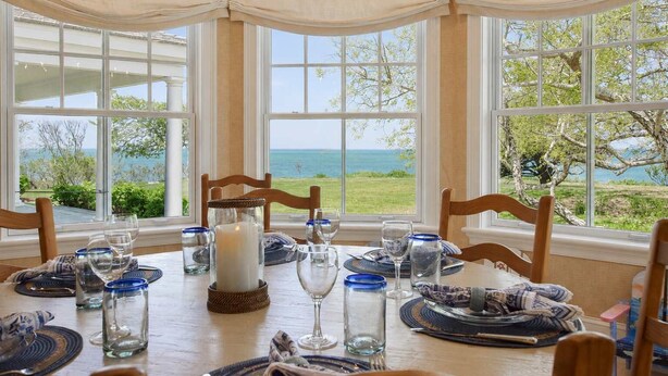 A dining table set for four with a view of the ocean. - Private Beach, Sweeping Water Views, Game Room! (Brewster)