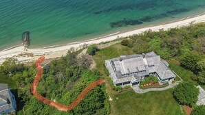 An aerial view of a coastal property with a large house, a beach, and a stone structure near the water. - Private Beach, Sweeping Water Views, Game Room! (Brewster)