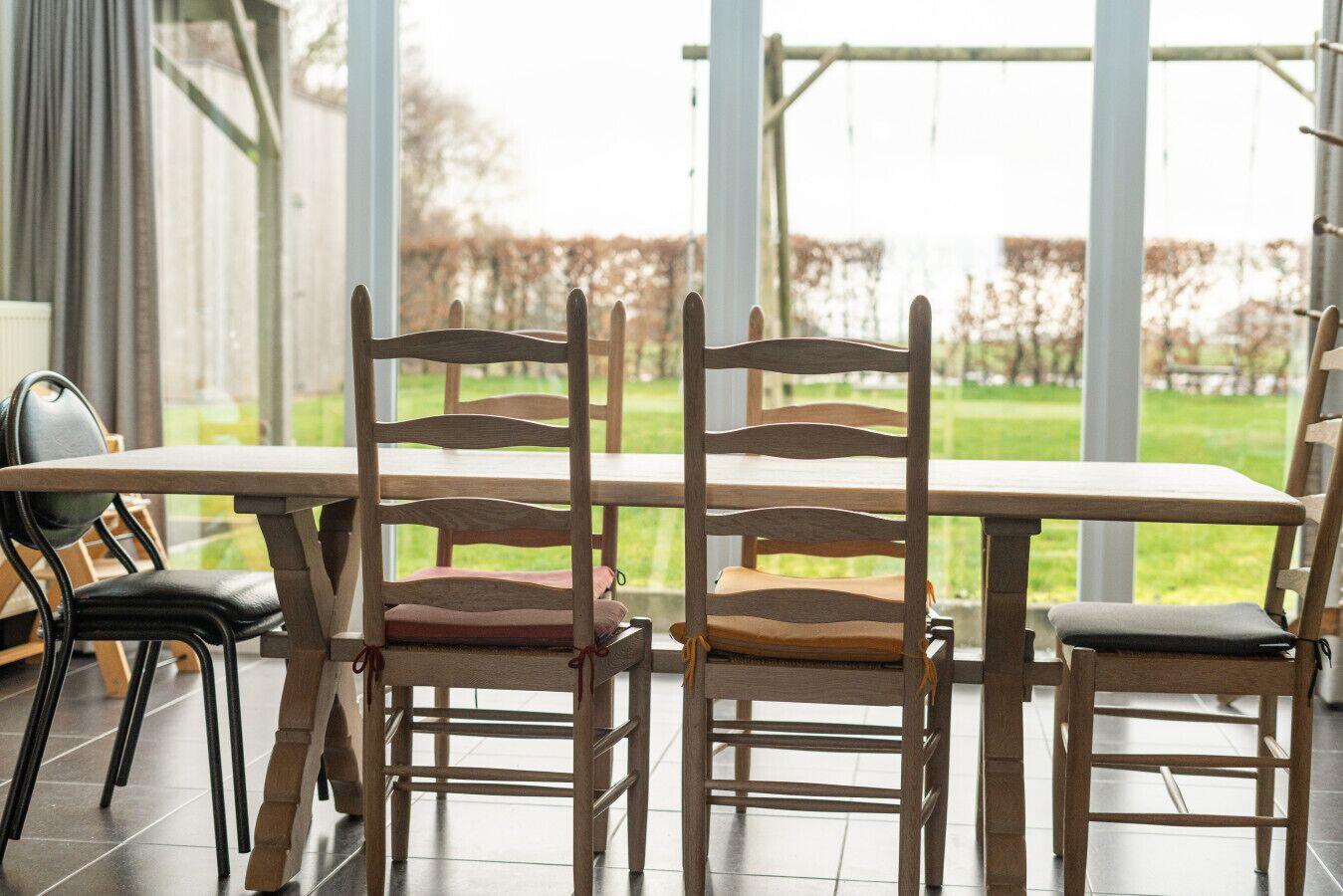 A dining area with a long table and wooden chairs with cushioned seats.