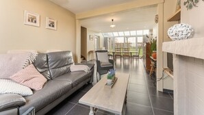 Uma sala de estar com sofá de couro, uma mesa de centro e um espaço de jantar com cadeiras e mesa.