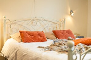 Ein Bett mit Metallgestell, zwei Kissen, einer Decke und einer Strickdecke.