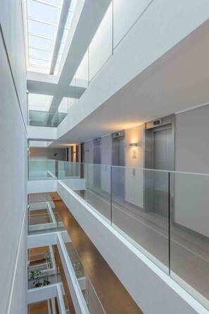 A modern interior with a glass railing, a staircase, and an elevator. - Málaga EXC I Chic 1 BR Apartment in El Golf (Santiago)