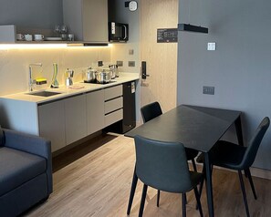 A modern kitchen with a dining area, featuring a microwave, kettle, and cabinets. - One Manquehue EXC | Bright 1BR Apartment (Santiago)