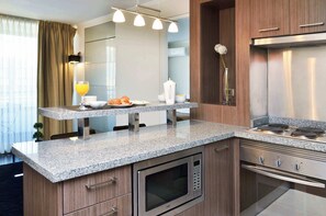 Eine moderne Küche mit Granit Arbeitsplatten, Edelstahlgeräten und einer eingebauten Mikrowelle.