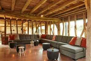Un'ampia zona giorno con un grande divano componibile, tavolini rotondi e soffitto in legno.
