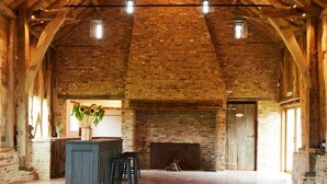 A spacious hall with a high wooden ceiling, a fireplace, and a bar area.