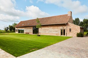 Un grande edificio in mattoni con tetto in tegole, un prato e un vialetto lastricato.