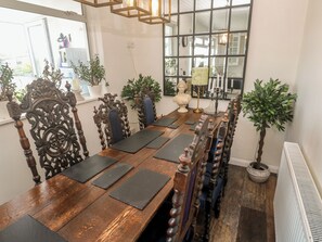 A dining area with a wooden table, chairs, and potted plants. - 4 Cardell Way (Newquay)
