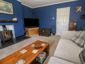 A living room with a fireplace, a television, a sofa, and a coffee table with playing cards. - 4 Cardell Way (Newquay)