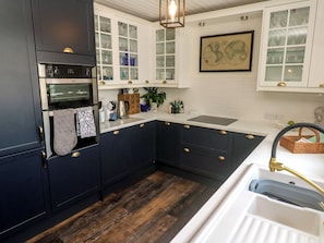 A kitchen with dark cabinetry, white countertops, a built-in oven, a sink, and a hanging light fixture. - 4 Cardell Way (Newquay)