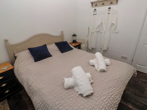 A neatly made bed with a beige quilt, two pillows, and two rolled towels. - 4 Cardell Way (Newquay)