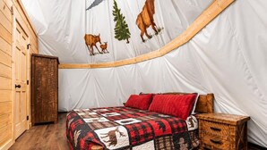 A cozy room with a bed, a wooden nightstand, and a door.
