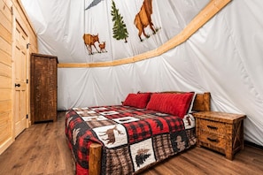 A cozy room with a bed, a wooden nightstand, and a door.
